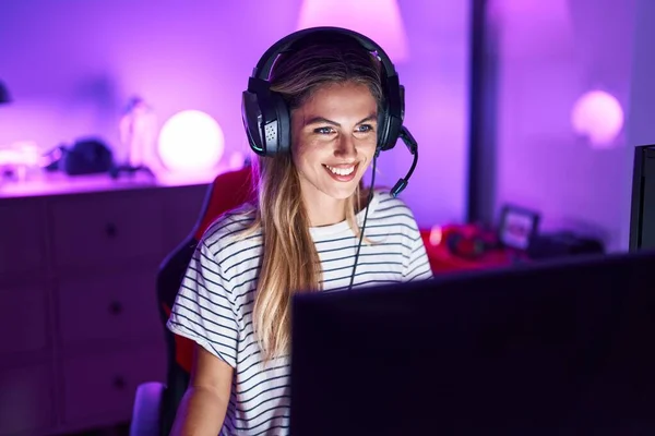 若いですブロンド女性再生ビデオゲーム見て正と幸せな立ちと笑顔とともにA自信を持って笑顔ショー歯 — ストック写真
