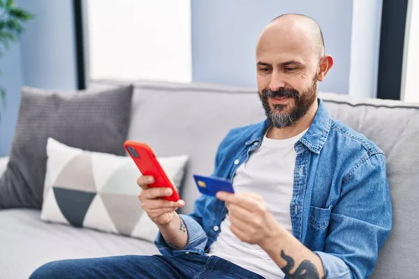 Young Bald Man Using Smartphone Credit Card Sitting Sofa Home — Stock fotografie