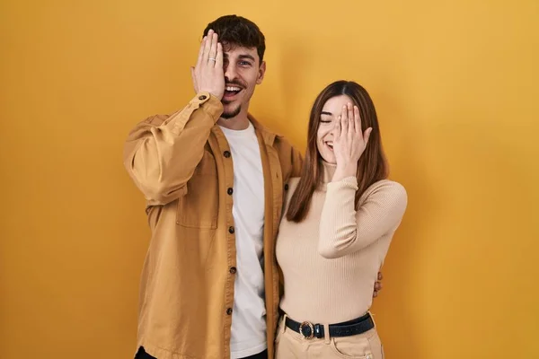 Sarı Arka Planda Duran Genç Spanyol Çift Bir Gözünü Eliyle — Stok fotoğraf