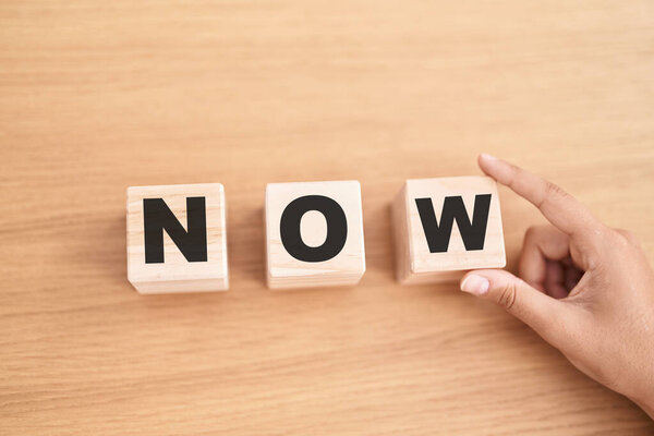 Женщина держит в руках кубики с теперь слово на столе