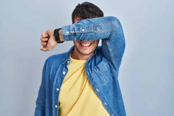 Νεαρός Ισπανός Στέκεται Πάνω Από Μπλε Φόντο Καλύπτει Μάτια Χέρι — Φωτογραφία Αρχείου