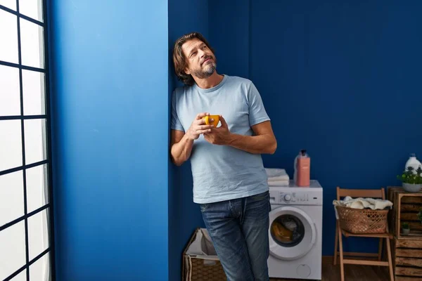 中年男子在洗衣房自信地喝咖啡 — 图库照片
