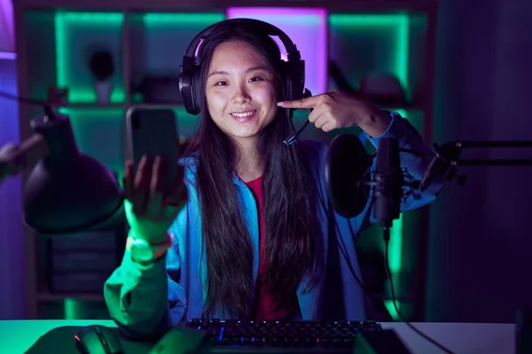 stock image Young asian woman playing video games with smartphone smiling cheerful showing and pointing with fingers teeth and mouth. dental health concept. 