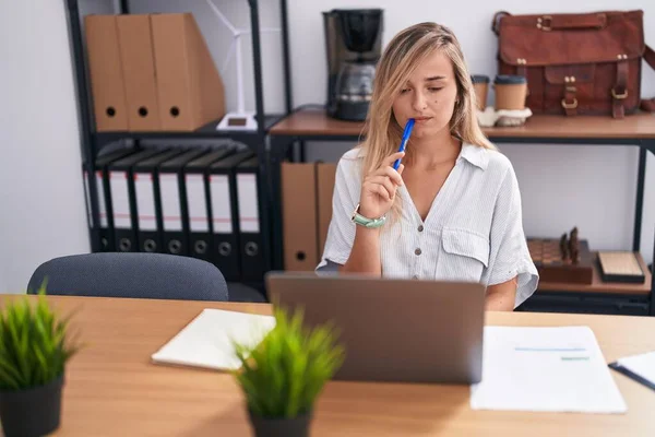 若いですブロンド女性ビジネスワーカー使用ノートパソコンとともに疑いの表情でオフィス — ストック写真