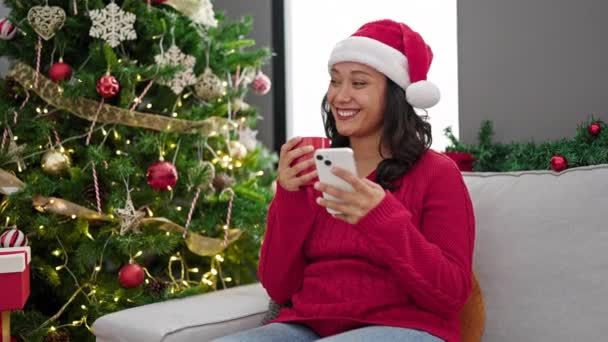 Νεαρή Όμορφη Ισπανόφωνη Γυναίκα Χρησιμοποιώντας Smartphone Πίνοντας Καφέ Γιορτάζοντας Χριστούγεννα — Αρχείο Βίντεο