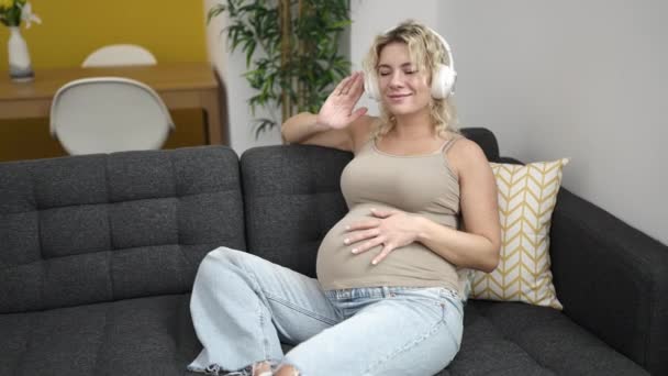 Молодая Беременная Женщина Слушает Музыку Трогает Живот Танцует Дома — стоковое видео