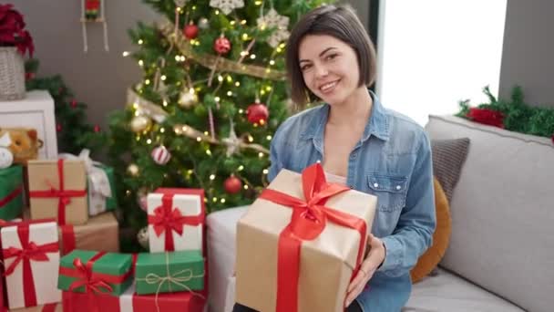 年轻的高加索女人抱着圣诞礼物坐在家里的沙发上 — 图库视频影像