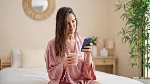 Young Beautiful Hispanic Woman Using Smartphone Drinking Coffee Bedroom — Stock video