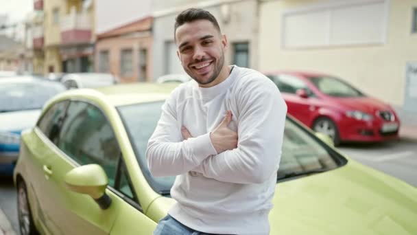 Ung Latinamerikansk Man Ler Säker Sitter Bilen Med Armarna Korsade — Stockvideo