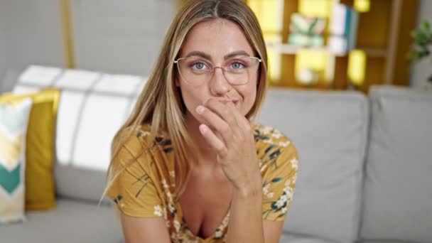 Νεαρή Ξανθιά Γυναίκα Κάθεται Στον Καναπέ Κάνοντας Χειρονομία Από Κοντά — Αρχείο Βίντεο