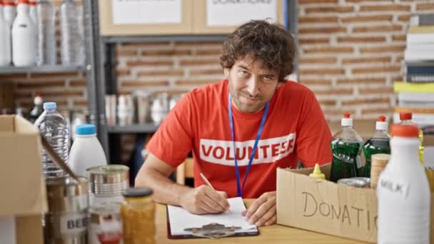 Jovem Hispânico Voluntário Escrevendo Área Transferência Sorrindo Centro Caridade — Vídeo de Stock