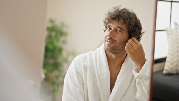 Young Hispanic Man Wearing Bathrobe Cleaning Ear Cotton Swab Looking — Stock Video