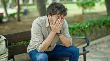 Parkta bankta oturan genç İspanyol stresli adam.