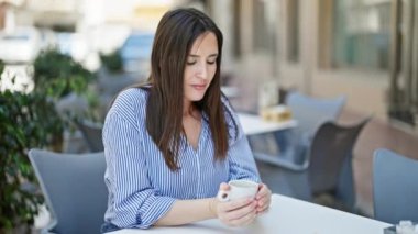 Kahve dükkanının terasında oturan kahve görünümlü saati içen genç, güzel İspanyol kadın.