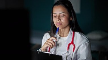 Genç, güzel İspanyol kadın doktor klinikte bilgisayar kullanarak tıbbi rapor yazıyor.