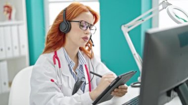 Videodaki genç kızıl saçlı kadın doktor klinikteki dokunmatik sayfaya yazı yazıyor.