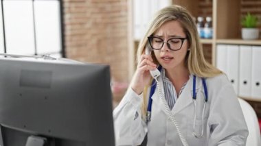 Genç sarışın doktor klinikte bilgisayarla konuşuyor.