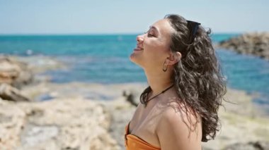 Young beautiful hispanic woman tourist wearing bikini breathing at beach
