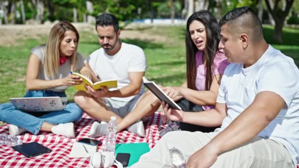 公園で勉強しているノートパソコンの読書本を使っている学生のグループ — ストック動画