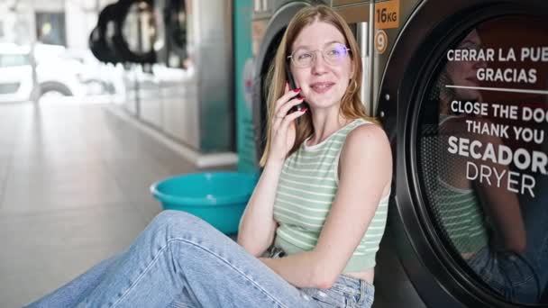 Νεαρή Ξανθιά Γυναίκα Μιλάει Στο Smartphone Περιμένοντας Πλυντήριο Στο Πλυσταριό — Αρχείο Βίντεο