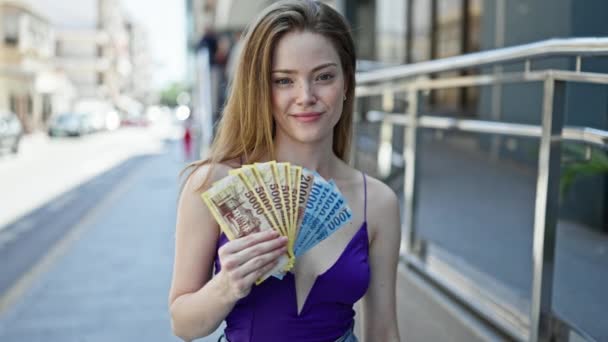年轻的金发女人带着饥饿的福林钞票在街上笑得很自信 — 图库视频影像