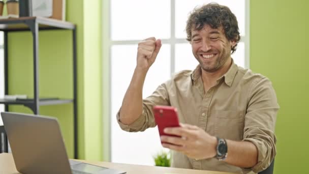Νέοι Ισπανοί Εργαζόμενοι Επιχείρηση Άνθρωπος Χρησιμοποιώντας Smartphone Γιορτάζει Στο Γραφείο — Αρχείο Βίντεο