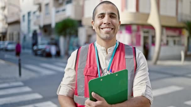 Joven Hispano Voluntario Sonriendo Sujetando Portapapeles Calle — Vídeo de stock