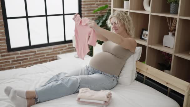 Young Pregnant Woman Holding Baby Clothes Sitting Bed Bedroom — Video Stock