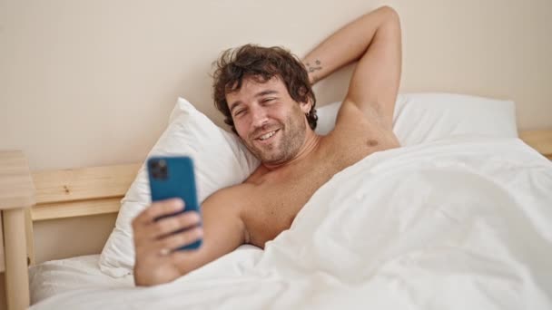 Молодий Іспаномовний Чоловік Лежить Ліжку Сорочки Маючи Відеодзвінок Спальні — стокове відео