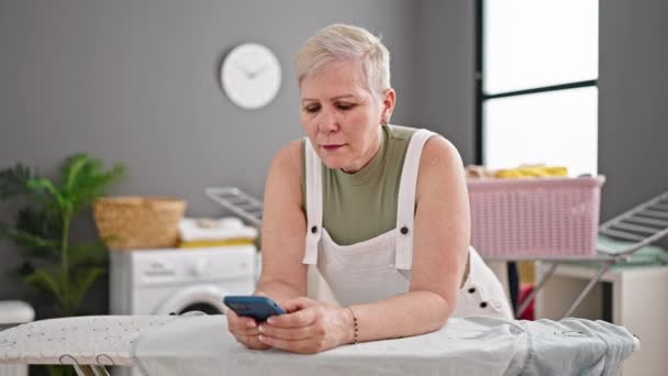 Mujer Pelo Gris Mediana Edad Usando Teléfono Inteligente Apoyado Tabla — Vídeos de Stock