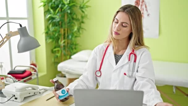 Dokter Wanita Pirang Muda Menggunakan Laptop Memegang Botol Obat Klinik — Stok Video