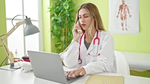 年轻的金发女医生在诊所用手提电脑打电话 — 图库视频影像