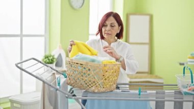 Middle age woman hanging clothes on clothesline at laundry room