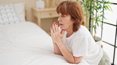 Yatak odasında dua eden orta yaşlı bir kadın.