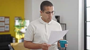 Genç İspanyol iş adamı. Ofiste kahve içip evrak okuyor.