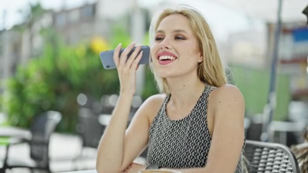 Νεαρή Ξανθιά Γυναίκα Που Ακούει Φωνητικό Μήνυμα Από Smartphone Κάθεται — Αρχείο Βίντεο