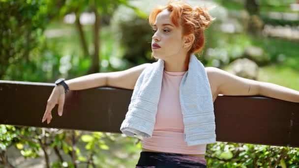 Young Redhead Woman Smiling Wearing Sportswear Sitting Bench Park — Stock Video