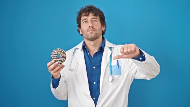 年轻的营养师牵着甜甜圈 用大拇指在孤立的蓝色背景上做着俯卧撑动作 — 图库视频影像