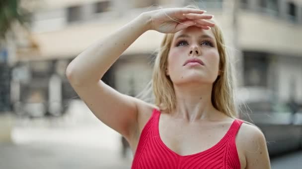 Молодая Блондинка Смотрит Небо Прикрывая Солнце Рукой Улице — стоковое видео