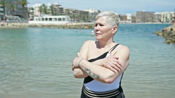 中年白发女游客穿着泳衣在海滩上拥抱自己 — 图库视频影像