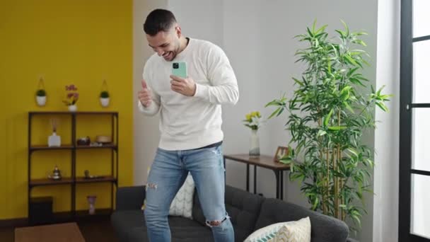 Νεαρός Ισπανός Άντρας Χαμογελάει Αυτοπεποίθηση Χορεύοντας Στον Καναπέ Στο Σπίτι — Αρχείο Βίντεο