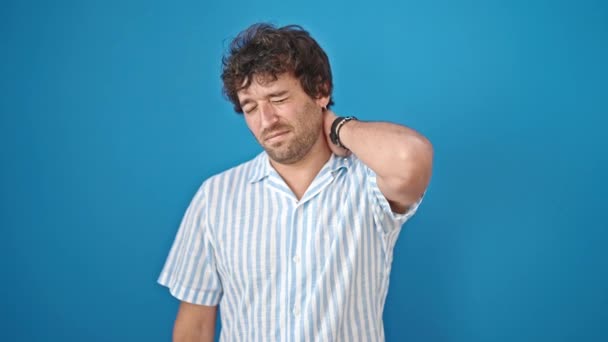 Jonge Spaanse Man Lijdt Aan Cervicale Pijn Geïsoleerde Blauwe Achtergrond — Stockvideo