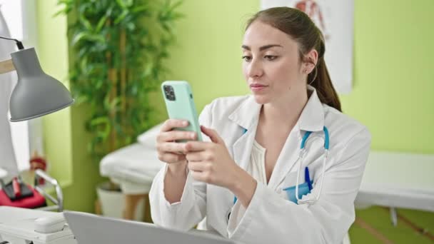 Klinikte Çalışan Akıllı Telefonu Kullanarak Gülümseyen Güzel Spanyol Kadın Doktor — Stok video