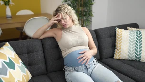 Mujer Embarazada Joven Sentada Sofá Con Expresión Estresada Tocando Vientre — Vídeos de Stock