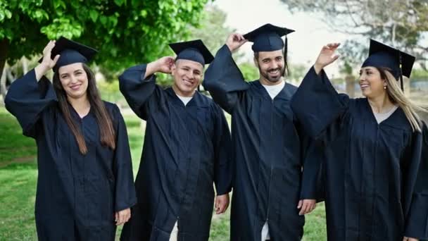 学生のグループは 大学キャンパスでキャップを飛ばす自信を持って笑顔を卒業しました — ストック動画