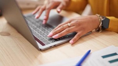 Afrika kökenli Amerikalı kadın ekommerans işçisi ofiste rahat bir ifadeyle dizüstü bilgisayar kullanıyor.