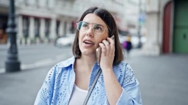 Genç ve güzel İspanyol kadın gülümsüyor mutlu bir şekilde Viyana sokaklarında telefonla konuşuyor.