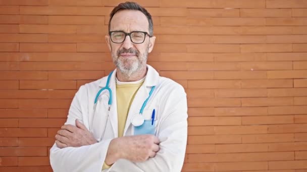 Médico Hombre Mediana Edad Sonriendo Confiado Pie Sobre Fondo Ladrillo — Vídeos de Stock