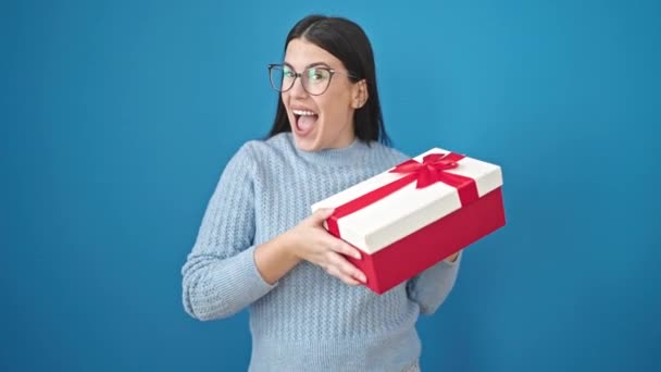 Jonge Hispanic Vrouw Glimlachen Holding Gift Geïsoleerde Blauwe Achtergrond — Stockvideo