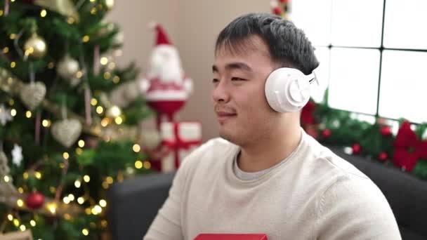 Mladý Číňan Poslouchá Hudbu Drží Dárek Vánočního Stromečku Doma — Stock video